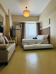 ein großes Schlafzimmer mit zwei Betten und einer Couch in der Unterkunft KBrothers - Chic Studio in the Heart of it All! in Cagayan de Oro