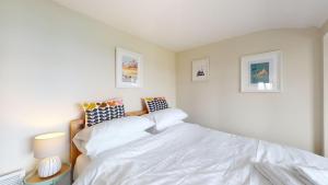 a bedroom with a white bed and two pictures on the wall at E08 Boness E8, Riviere Towans in Hayle