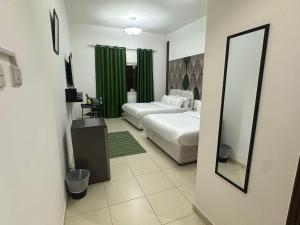 a hotel room with two beds and a mirror at AlWasl Guesthouse by PHM in Dubai