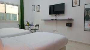 a hotel room with two beds and a flat screen tv at AlWasl Guesthouse by PHM in Dubai +20 photos