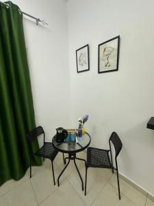 a table and chairs in a room with a green curtain at AlWasl Guesthouse by PHM in Dubai