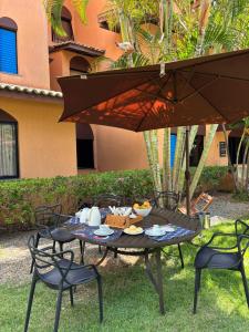 a table with a plate of food on it under an umbrella at Flat em Genipabu Summer House in Guarajuba