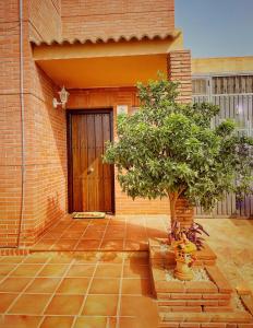 a tree in front of a building with a door at Villa EMMA - Chalet familiar con jardín y parking en Málaga in Málaga