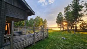 a barn with a fence next to a field at Authentic Finnish Lakeside Cottage in Lusila