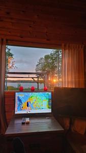 a living room with a large window and a television at Authentic Finnish Lakeside Cottage in Lusila