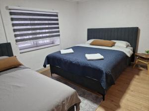 a bedroom with two beds and a window with blinds at "BIJELA" Apartments with AC, outdoor fireplace and terrace in Jablanica