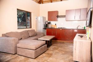 a living room with a couch and a kitchen at Falcon Lodge ET in Bela-Bela