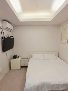 a bedroom with a white bed and a flat screen tv at GaGa Hotel dongdaemun in Seoul