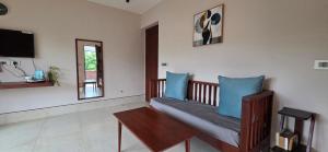 a living room with a bench with blue pillows at Nirmala's Farmhouse - The Blu room in Kuttālam