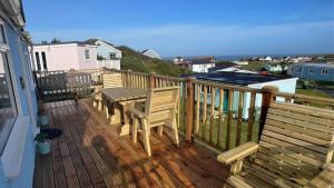 a wooden deck with a wooden table and benches at E08 Boness E8, Riviere Towans in Hayle