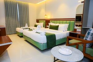 a hotel room with two beds and a table at MR Suites Dharwad in Dhārwād