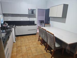a kitchen with white cabinets and a table and chairs at Casa a 4 km do centro e Shopping Campo Grande in Campo Grande +6 photos