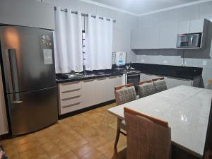 a kitchen with a refrigerator and a table with chairs at Casa a 4 km do centro e Shopping Campo Grande in Campo Grande