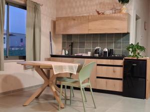 a kitchen with a wooden table and green chairs at שיר ערש in Giv'at Yo'av