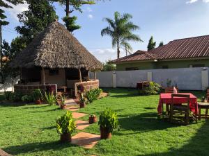 a hut with a grass roof in a yard at Sisama Lodge in Msaranga