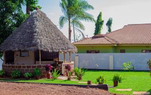 a small hut with a thatched roof in front of a house at Sisama Lodge in Msaranga