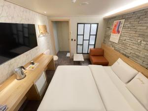 a living room with a white bed and a television at Gallery Motel in Seongnam