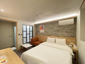 a bedroom with a large white bed and a chair at Gallery Motel in Seongnam