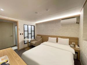 a bedroom with a large white bed and a chair at Gallery Motel in Seongnam