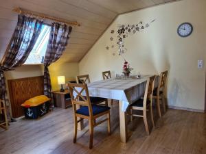a dining room table with chairs and a clock on the wall at Fewo Perle Medebach in Medebach