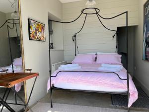 a bedroom with a bed with pink sheets and a mirror at The Stables in Corsley