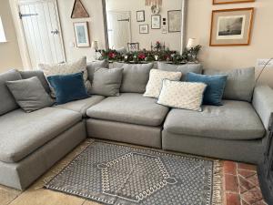 a living room with a gray couch with blue pillows at The Stables in Corsley
