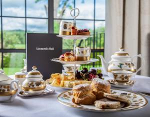 ein Tisch, gedeckt mit Tellern mit Gebäck und Teesets in der Unterkunft Llangoed Hall in Bronllys