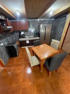 a kitchen with a wooden table and some chairs at Cabañas Maite Panguipulli Calafquen 2 in Huellahue +3 photos