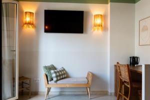 a room with a chair and a television on a wall at Rooms by JovA in El Campello