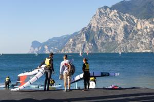 a group of people standing on a beach near the water at Hotel Villa Claudia in Nago-Torbole +39 photos