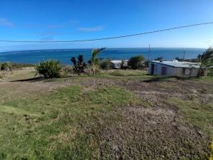 a house on a hill with the ocean in the background at Paradis des Pailles-en-Queue in Port Mathurin