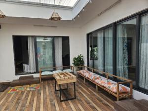 a living room with two benches and large windows at Getaway to Mauritius - Évasion à Île Maurice in Eau Bleue