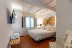 a bedroom with a white bed and a television at Natural&Mente Apartamentos Valle del Jerte in El Torno +165 photos