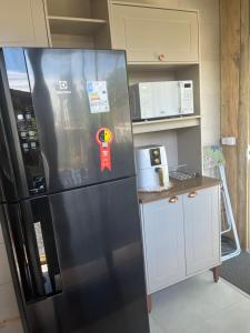 a black refrigerator in a kitchen with a counter at Casa Vidro Mar in Bombinhas