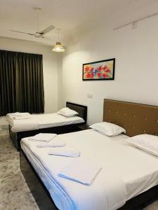 a room with two beds and a tv on the wall at Kozy Cottage udaipur in Udaipur