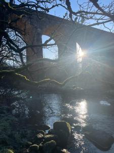a bridge over a river with the sun shining at West Coast Whistlestop in Ochiltree +14 photos