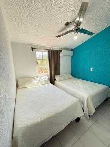 two beds in a room with a blue wall at Casa Morroken Ixtapa con Alberca in Ixtapa +20 photos