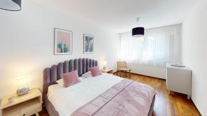 a bedroom with a large bed with pink pillows at Relax and Recharge By The Lake! Modern Morges Apartments, AP26 in Morges