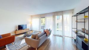 a living room with a couch and a tv at Relax and Recharge By The Lake! Modern Morges Apartments, AP26 in Morges