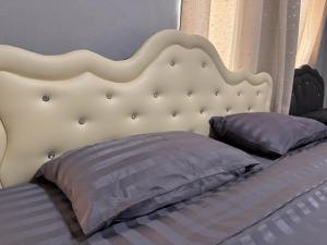 a bed with a white headboard and two pillows at Phak Ploen Home Stay in Ban Rae Mai Phai