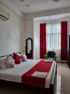 a bedroom with a large bed with red curtains at Wings Hotel & Hostel in Trincomalee +32 photos
