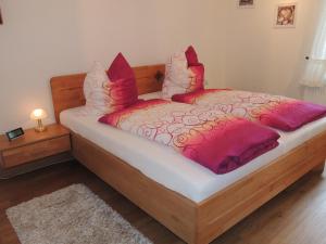 Schlafzimmer mit einem Bett mit roten und weißen Kissen in der Unterkunft Ferienhaus Snevern in Schneverdingen