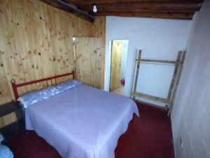 a bedroom with a white bed and wooden walls at Antonio House in Uspallata