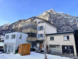 a building in front of a mountain in the snow at Revier beau jardin in Glarus