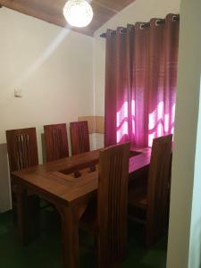 a dining room table with chairs and a pink curtain at Villa Golden Drift in Ahangama +13 photos