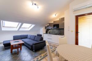 a living room with a blue couch and a kitchen at Apartments Padovan in Rab