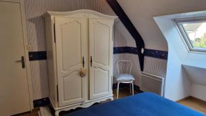 a bedroom with a white cabinet and a chair at les HAUTS de SAINT SATURNIN in Saint-Saturnin