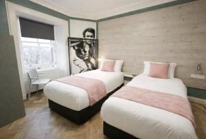 two beds in a hotel room with a picture on the wall at Revolver Edinburgh in Edinburgh