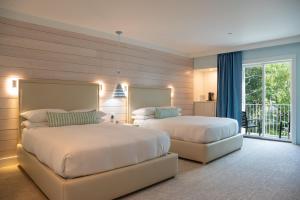 a bedroom with two beds and a balcony at The Colony Hotel Kennebunkport in Kennebunkport +41 photos