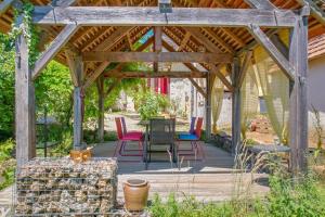 a wooden pergola with a table and chairs on a patio at Les Deux Canards Perdus in Rouffignac Saint-Cernin